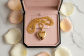 24K Gold Heart Locket Pendant Necklace displayed in a pink jewelry box with rose petals.