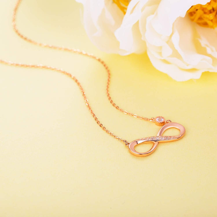 Infinity Necklace 925 Sterling Silver with rose gold infinity pendant and sparkling detail, on a soft yellow background.