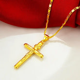 24K gold cross pendant necklace hanging on a red fabric background showcasing polished gold-tone finish.