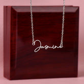 Personalized name necklace with the name Jasmine displayed, hanging in front of a wooden jewelry box.